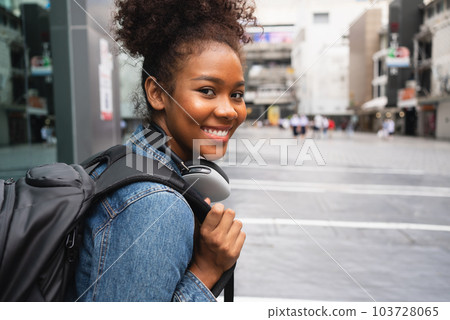 Smiling happy woman walking on street with backpack in city Smiling happy woman walking on street with backpack in city 103728065