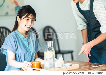 A young woman and a clerk in an apron taking brunch at a cafe A young woman and a clerk in an apron taking brunch at a cafe 103729084
