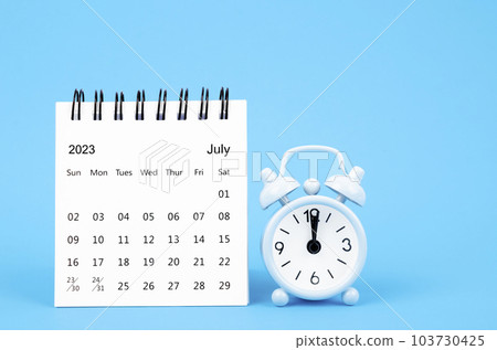 The July 2023 desk calendar and alarm clock on blue color background. The July 2023 desk calendar and alarm clock on blue color background. 103730425