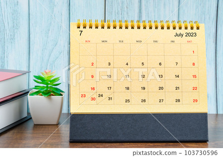 July 2023 Monthly desk calendar for the organizer to plan 2023 year with the books on wooden table. 103730596