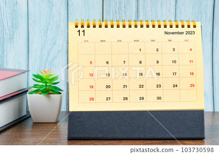 The November 2023 Monthly desk calendar for 2023 year with the books on blue wooden background. 103730598