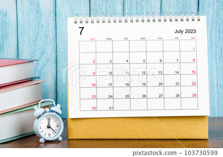 The July 2023 Monthly desk calendar for the organizer to plan 2023 year with alarm clock and books on wooden table. The July 2023 Monthly desk calendar for the organizer to plan 2023 year with alarm clock and books on wooden table. 103730599