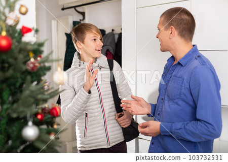 Guy saying goodbye father in entrance hall of apartment after christmas Guy saying goodbye father in entrance hall of apartment after christmas 103732531