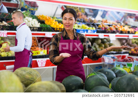 Friendly saleswoman offering fruits and vegetables in greengrocery store Friendly saleswoman offering fruits and vegetables in greengrocery store 103732691