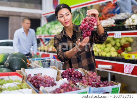 Woman choosing grape in greengrocer Woman choosing grape in greengrocer 103732735