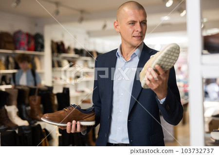 Man chooses and tests the strength of new demi-season shoes in shoe store Man chooses and tests the strength of new demi-season shoes in shoe store 103732737
