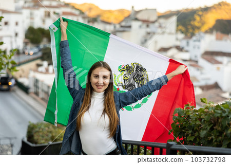 Excited young female traveler waving Mexican flag on street, sport fan supporter Excited young female traveler waving Mexican flag on street, sport fan supporter 103732798