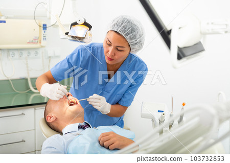 Dentist inspects male patient teeth Dentist inspects male patient teeth 103732853