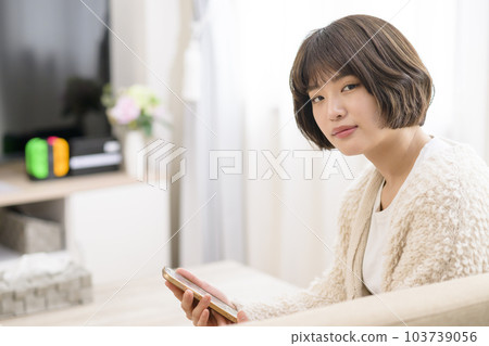 年輕女子在客廳看智慧型手機 年輕女子在客廳看智慧型手機 103739056
