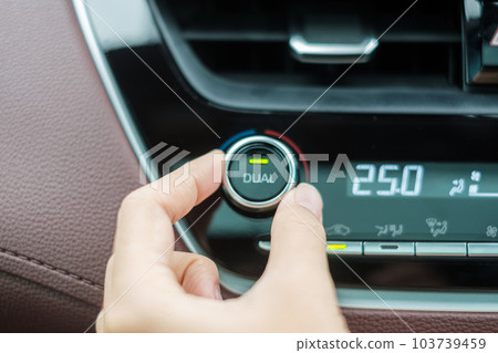 Woman hand adjusting temperature the air flowing during driving car on the road, air conditioner cooling system inside the car. Adjust, temperature and transport concept 103739459