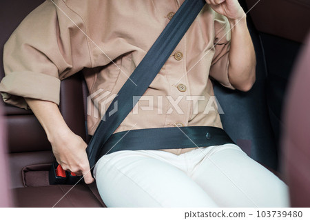 woman driver hand fastening seat belt during sitting inside a car and driving in the road. safety, trip, journey and transport concept woman driver hand fastening seat belt during sitting inside a car and driving in the road. safety, trip, journey and transport concept 103739480
