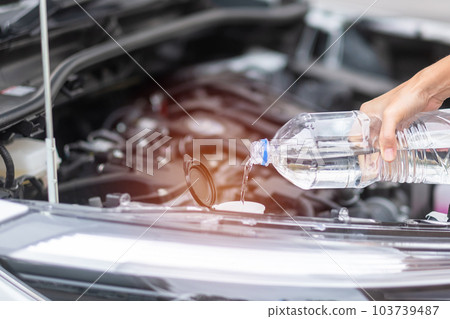 woman hand filing pure water in windscreen washer tank car. Self Maintenance, repair and problem concept woman hand filing pure water in windscreen washer tank car. Self Maintenance, repair and problem concept 103739487