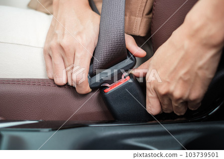 woman driver hand fastening seat belt during sitting inside a car and driving in the road. safety, trip, journey and transport concept woman driver hand fastening seat belt during sitting inside a car and driving in the road. safety, trip, journey and transport concept 103739501