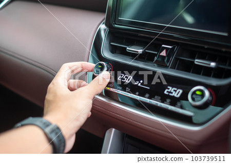 man hand adjusting temperature the air flowing during driving car on the road, air conditioner cooling system inside the car. Adjust, temperature and transport concept man hand adjusting temperature the air flowing during driving car on the road, air conditioner cooling system inside the car. Adjust, temperature and transport concept 103739511
