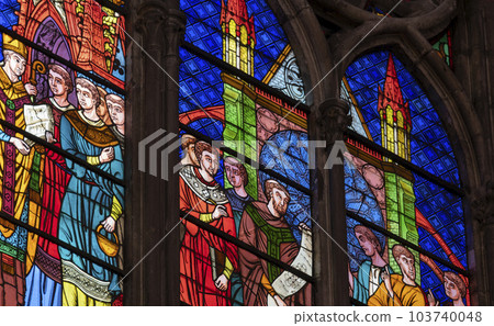 5 May 2023 St. Denis, France. Detail of stained glass depicting a cathedral in background of saints, clergy, and other men. 5 May 2023 St. Denis, France. Detail of stained glass depicting a cathedral in background of saints, clergy, and other men. 103740048