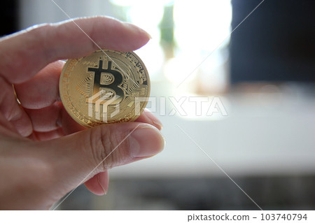 Hand hold gold bitcoin cryptocurrency on grey background. Physical bit coin. Digital currency Hand hold gold bitcoin cryptocurrency on grey background. Physical bit coin. Digital currency 103740794