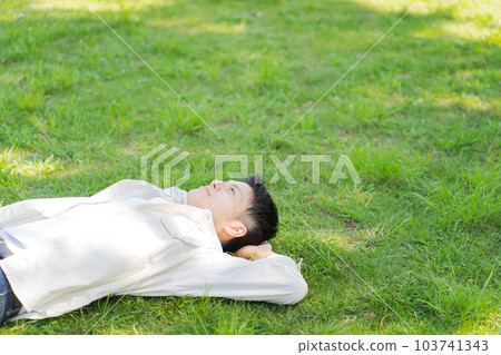 Photo of a man lying on the grass Photo of a man lying on the grass 103741343