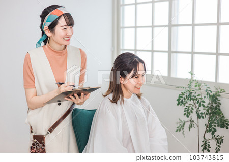理髮師為在美容院/美髮沙龍諮詢髮型和髮型的女性顧客提供諮詢 103743815