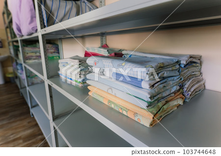 Linens piled neatly on shelves. There are folded bed sheets, towels, wash clothes 103744648
