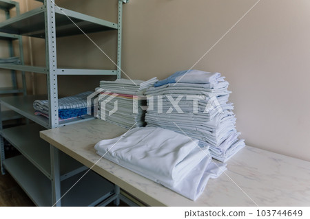 Linens piled neatly on shelves. There are folded bed sheets, towels, wash clothes Linens piled neatly on shelves. There are folded bed sheets, towels, wash clothes 103744649