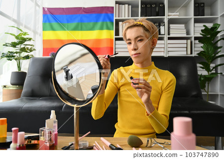 Smiling Asian gay man blogger filming daily makeup routine tutorial on smartphone. LGBTQ, domestic life and beauty concept 103747890