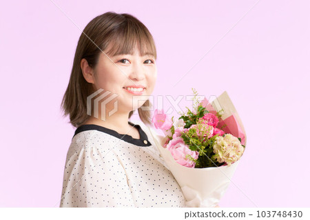 微笑的年輕女子手捧一束鮮花 微笑的年輕女子手捧一束鮮花 103748430