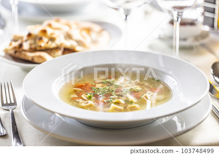 Hot chicken soup with small tortellini, carrot and greens on top Hot chicken soup with small tortellini, carrot and greens on top 103748499