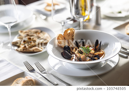 Fish soup with seafood served in an esthetic way on a plate in a restaurant 103748505