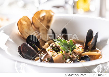 Detailed view of a mussels and seafood soup in a deep designer plate 103748506