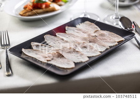 Thinly sliced veal with a tuna salsa served on a black rectangular plate Thinly sliced veal with a tuna salsa served on a black rectangular plate 103748511