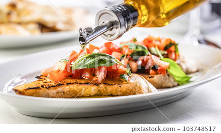 Detail of olive oil poured over bruschetta with basil and tomatoes 103748517