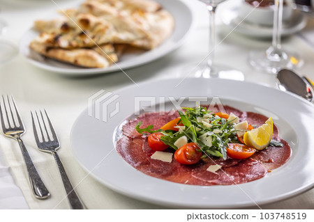 Typical Italian appetizer, carpaccio from veal or beef thinly sliced and served on a plate with salad 103748519