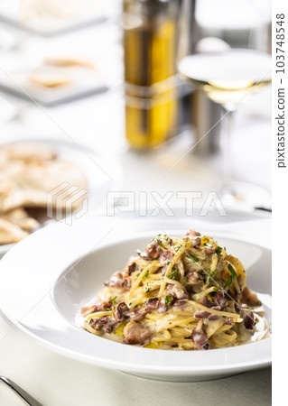 Typical Italian food, spaghetti carbonara, piled on a plate with its typical yellow and red color Typical Italian food, spaghetti carbonara, piled on a plate with its typical yellow and red color 103748548