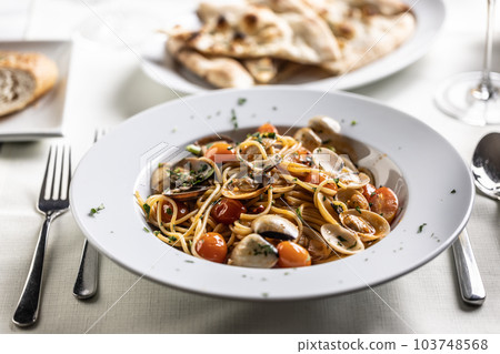 Plate full of spaghetti alle vongole e pomodorini served on a restaurant table 103748568