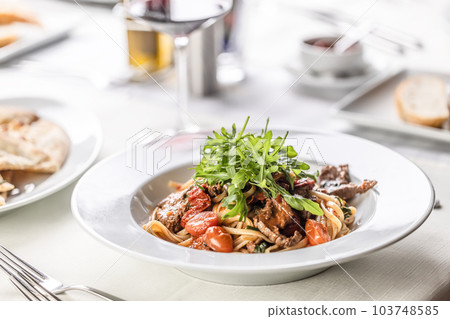 Italian coooking of linguine with meat, tomatoes and ruccola on top Italian coooking of linguine with meat, tomatoes and ruccola on top 103748585