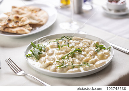 Italian gnocchi ai quatro formaggi with pizza bread on the side served on a table 103748588