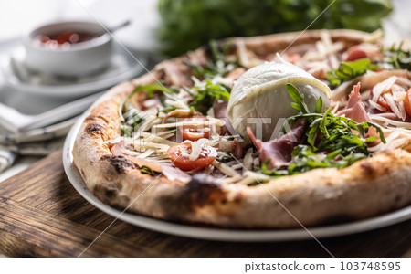 Ham, ruccola, tomatoes and cheese pizza with entire mozzarella di bufala Campana on top 103748595