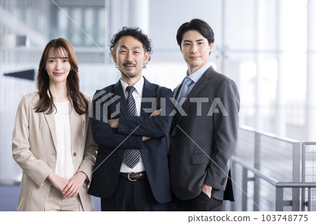 Business team of businessman with serious expression standing with arms crossed in office building Business team of businessman with serious expression standing with arms crossed in office building 103748775