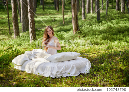 Young woman wakes up in a summer forest 103748798