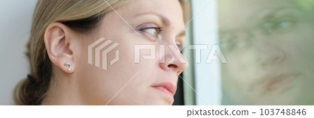 Sad woman is bored and looks out window 103748846