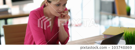 Businesswoman worried and biting her nails in front of laptop screen Businesswoman worried and biting her nails in front of laptop screen 103748869