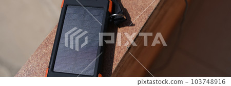 Solar power bank for charging mobile phone lying under rays of sun closeup Solar power bank for charging mobile phone lying under rays of sun closeup 103748916