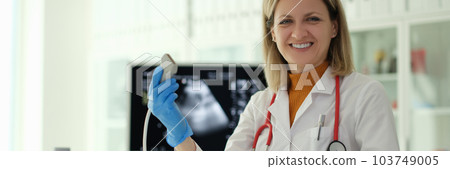 Smiling woman doctor holding ultrasound probe in her hands in clinic 103749005