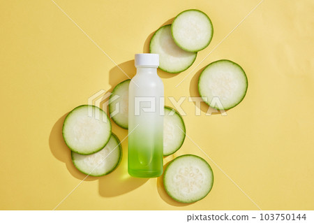 Unlabeled bottle in gradient green color put on some winter melon slices. Cosmetics, products for care and personal hygiene concept that extracted from Winter melon (Benincasa hispida) Unlabeled bottle in gradient green color put on some winter melon slices. Cosmetics, products for care and personal hygiene concept that extracted from Winter melon (Benincasa hispida) 103750144