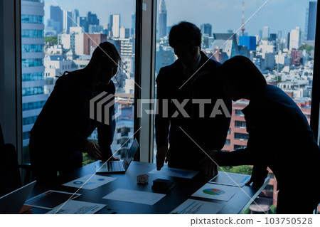 Silhouettes of men and women having a meeting in a high-rise building conference room 103750528