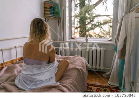 Woman reading a book in bed, lying on her stomach smiling happy and relaxed on a leisure day at home Woman reading a book in bed, lying on her stomach smiling happy and relaxed on a leisure day at home 103750845