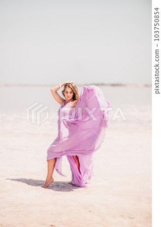 Woman pink salt lake. Against the backdrop of a pink salt lake, a woman in a long pink dress takes a leisurely stroll along the white, salty shore, capturing a wanderlust moment. Woman pink salt lake. Against the backdrop of a pink salt lake, a woman in a long pink dress takes a leisurely stroll along the white, salty shore, capturing a wanderlust moment. 103750854