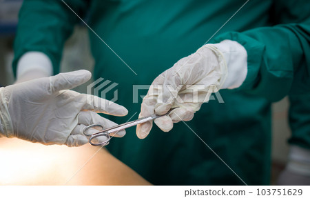 Closeup shot in the operating room, assistant hands out instruments to surgeons during operation. 103751629