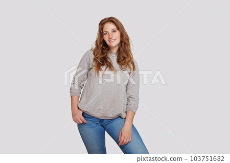 Perfect confident smiling redhead woman in grey longsleeve and blue jeans standing  103751682