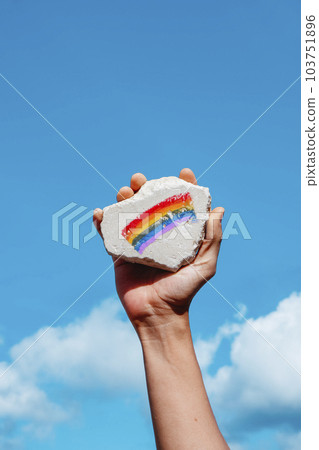 holds rock with a rainbow flag in his hand 103751896